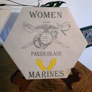 Hexagonal plaque with "women parris island marines" and an emblem, displayed on a wooden stand.