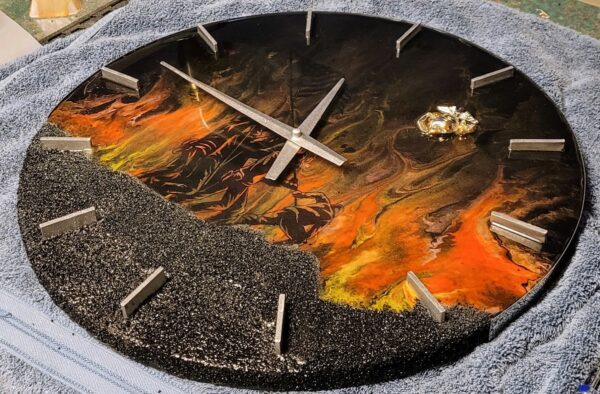A decorative Iwo Jima Resin Clock featuring a fiery landscape design with molten lava and rocky textures, partially covered by a cool, grey textured material.