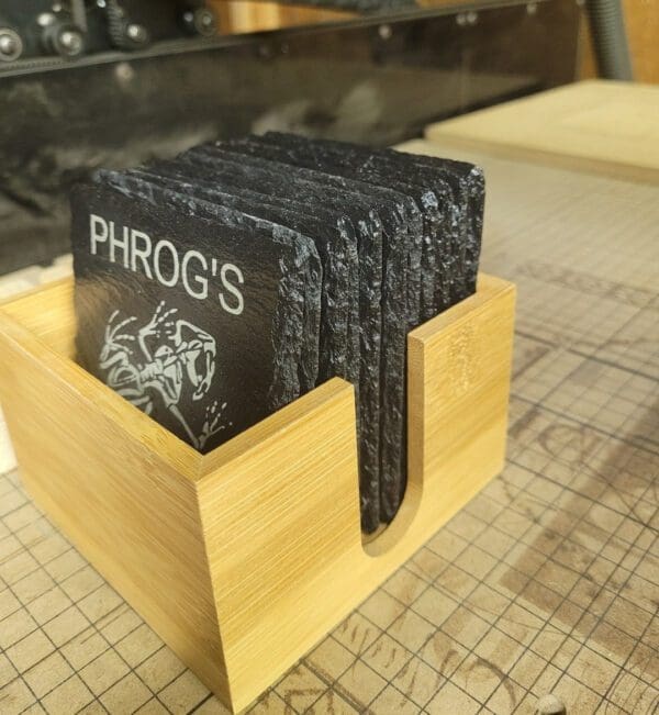 A wooden box holding four coasters with phrog 's logo on them.