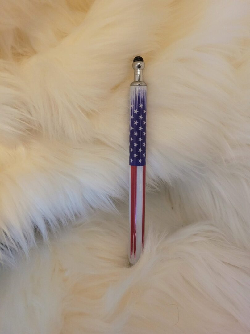 A Custom Pen w/Stylus with an American flag design lying on a fluffy white fur background.