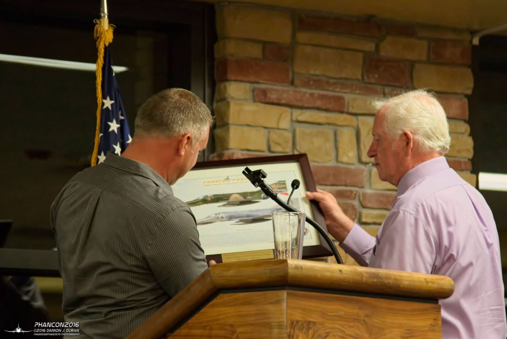 A man is speaking to another man in front of a microphone.