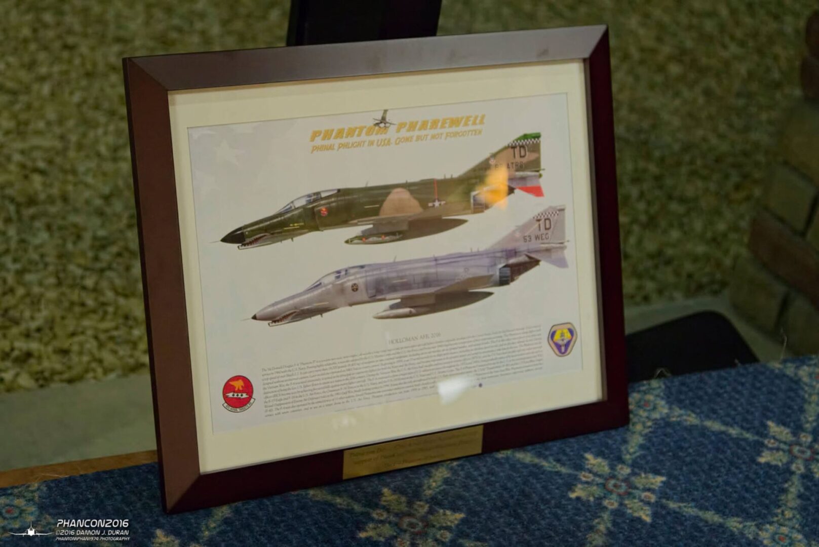 A framed picture of two fighter jets on the floor.