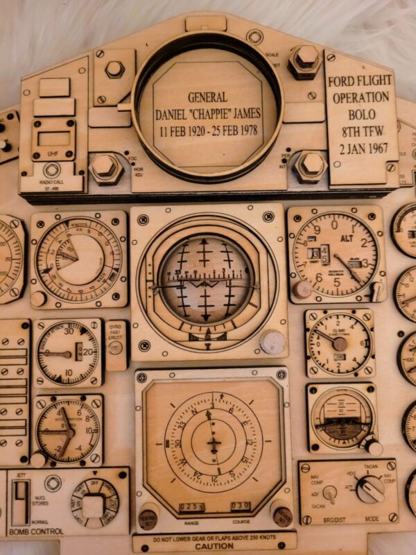 An intricately designed Legend Plaque with engraved dials and gauges resembling an aircraft control panel, including labels like “Ford Flight Operation” and a tribute to General Daniel James.