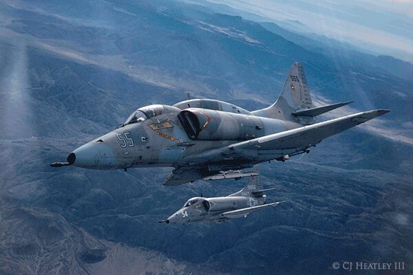 Two fighter jets flying in the sky over a mountain range.