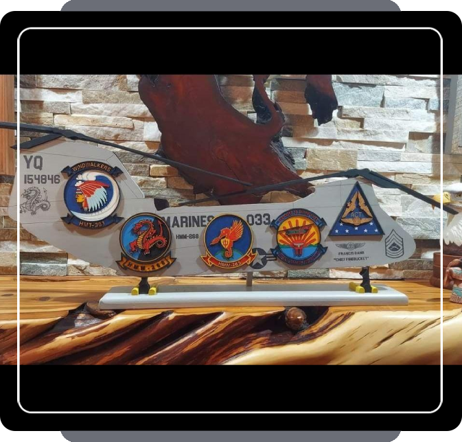 A decorated military oar mounted on a wooden wall, featuring custom art pieces and symbols related to the U.S. Marine Corps.